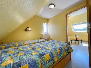 a bedroom with a bed with a blue and yellow quilt at Apartment Résidence jaune et rose-3 by Interhome in Marckolsheim