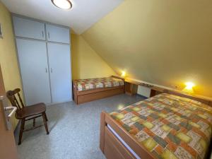 1 dormitorio pequeño con 2 camas y 1 silla en Apartment Résidence jaune et rose-4 by Interhome, en Marckolsheim
