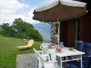 a table and chairs with an umbrella on a patio at Holiday Home Rustico Tecc du Martin by Interhome in Leontica