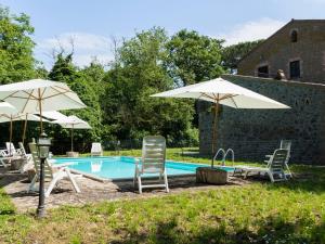 einen Pool mit 2 Stühlen und Sonnenschirmen in der Unterkunft Apartment La Capraccia-5 by Interhome in Bagnoregio