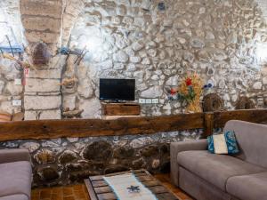 a living room with a stone wall with a tv at Apartment La Capraccia-5 by Interhome in Bagnoregio