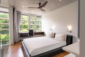 Ecoloft Jababeka Golf في سيكارانغ: غرفة نوم بسرير أبيض ومروحة سقف