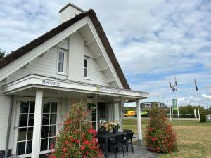 a white house with a table and flowers in front of it at Holiday Home Plevier Comfort-1 by Interhome in Noordwijk +13 photos