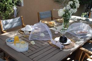 una mesa de madera con comida y sombrillas. en Chambre d'hôtes Les Magnolias, en Pontpierre