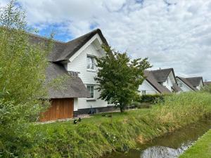 een huis met een rieten dak naast een rivier bij Holiday Home Alk 6 by Interhome in Noordwijk +12 foto's