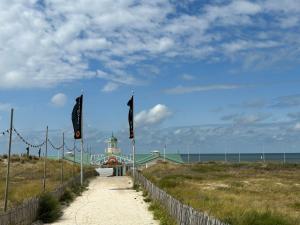un camino que conduce a un edificio en una playa con banderas en Holiday Home de Witte Raaf-2 by Interhome en Noordwijk