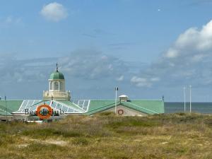 een gebouw met een groen dak naast de oceaan bij Holiday Home de Witte Raaf-2 by Interhome in Noordwijk