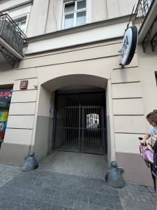 a woman standing in front of a building with a gate at Apartment in the center in Łódź