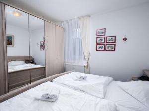 Schlafzimmer mit einem weißen Bett und einem Spiegel in der Unterkunft Apartment Baltrum-Badestrasse by Interhome in Norddeich