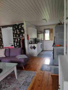 ein Wohnzimmer mit einem lila Sofa und einer Küche in der Unterkunft Mökki Mannervaarassa, Joensuussa in Mannervaara
