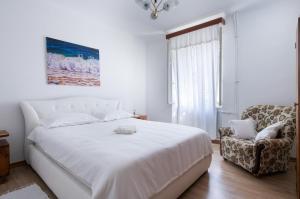 een witte slaapkamer met een bed en een stoel bij Apartment Da Lia in Momjan