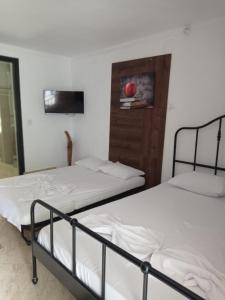 2 Betten in einem Zimmer mit einem TV an der Wand in der Unterkunft Casa Marronne in Costinești
