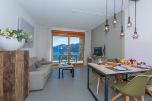 a living room with a couch and a table with chairs at Residence degli Oleandri 2A in Argegno