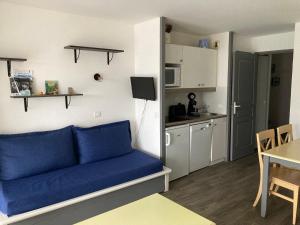 uma sala de estar com um sofá azul e uma cozinha em Appartement Douarnenez Résidence en bord de plage em Douarnenez