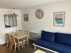 a living room with a couch and a table and a clock at Appartement Douarnenez Résidence en bord de plage in Douarnenez