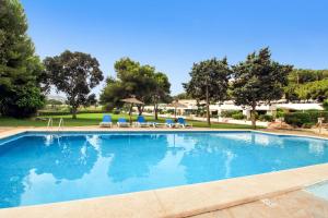 a large swimming pool with chairs and trees at Two Bedroom Golf Bungalow On La Manga Club in Atamaría