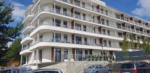 a white building with cars parked in front of it at Apartament Happy 46 Hampton z klimatyzacją - tuż przy plaży!!! in Sianozety