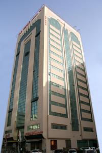 a tall building with cars parked in front of it at Spark Residence Hotel in Sharjah