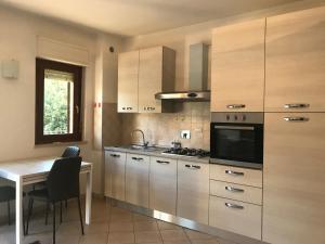 a kitchen with wooden cabinets and a table and a microwave at Casetta in Collina in Castello delle Forme