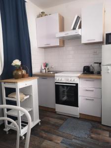 a kitchen with white appliances and a table and a chair at Apartman studio Otium in Pirovac