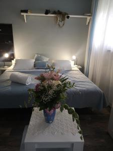 a bedroom with a bed and a vase of flowers on a table at Apartman studio Otium in Pirovac