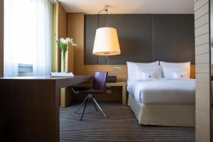 a hotel room with a bed and a desk and a desk at InterContinental Genève by IHG in Geneva