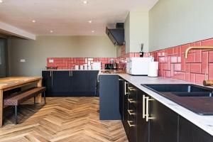 a kitchen with black cabinets and a wooden floor at High Tide in Redcar