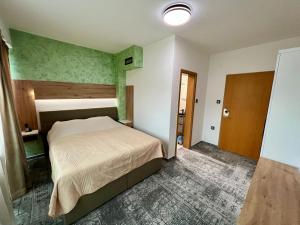 ein Schlafzimmer mit einem Bett und einer grünen Wand in der Unterkunft Hotel Brkić Sarajevo Airport - Free Parking in Sarajevo