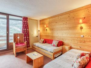 a room with a wooden wall with a bed and a chair at Apartment Chanteneige 301 by Interhome in Les Menuires +34 photos