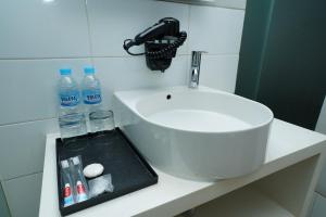 - un lavabo dans la salle de bains avec des bouteilles d'eau sur un comptoir dans l'établissement Grand Safran Hotel Pangkalpinang, à Pangkal Pinang