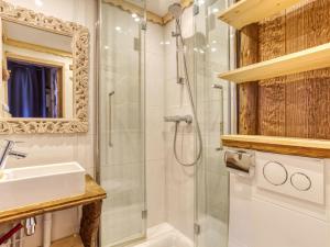 ein Bad mit einer Dusche, einem Waschbecken und einem Spiegel in der Unterkunft Apartment Belleville Caron-12 by Interhome in Les Menuires