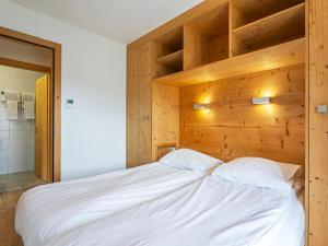 Apartment T-Resort La Tzoumaz 3p6 by Interhome في لا تزوماز: غرفة نوم بسرير ابيض كبير وبجدار خشبي