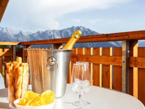 ラ・ズマにあるApartment T-Resort La Tzoumaz 2p4 vue vallée by Interhomeの- グラス付きのテーブルの上のバケツに入ったシャンパン1本
