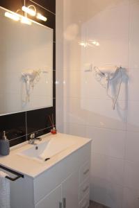a white bathroom with a sink and a mirror at Casa Carvalho Laranjo in Nazaré