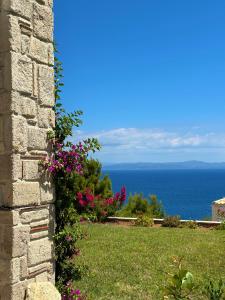 a stone wall with flowers and the ocean in the background at Afytos sea view in Afitos