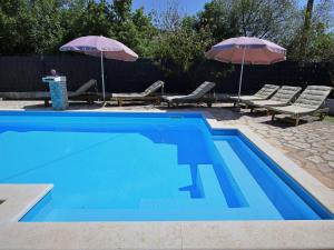 una piscina azul con 2 sombrillas y 2 sillas en Holiday Home Labin by Interhome, en Labin