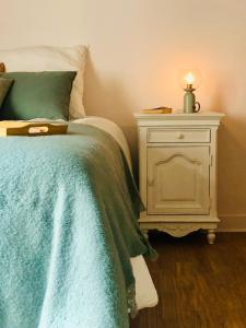 Un dormitorio con una cama y una mesita de noche con una vela en L’AMANTINE Chambres d’hôtes et gîte, en Bourges