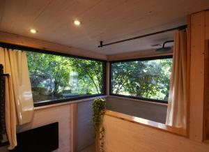 2 ventanas en una habitación con árboles en el fondo en L'Abri des Rêves en Aydat