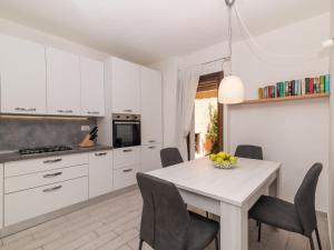 una cucina con mobili bianchi, tavolo e sedie di Apartment Trudi by Interhome a Cannigione
