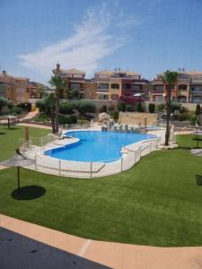 Excelente Duplex en Altaona golf resort-piscinas في مورسية: مسبح وسط حديقة فيها مباني