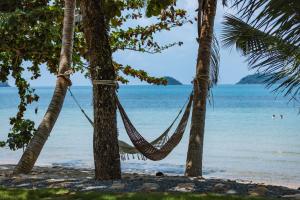 a hammock hanging between two palm trees on a beach at Sea Escape Koh Chang in Ko Chang