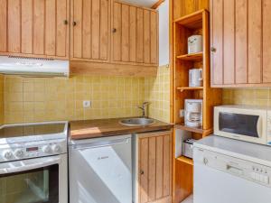 una cucina con armadi in legno, lavandino e lavastoviglie di Apartment Chanteneige La Croisette-5 by Interhome a Les Menuires
