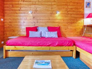 una camera con un letto con cuscini rossi e un tavolo di Apartment Chanteneige La Croisette-5 by Interhome a Les Menuires