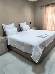 a large white bed with white sheets and pillows at No 12 in Rustenburg