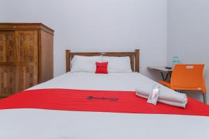 a bed with a red blanket and two towels on it at RedDoorz At Pondok Candra in Surabaya