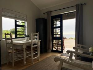 a dining room with a table and chairs and windows at Accommodation @Sea Trader in St. Helena Bay