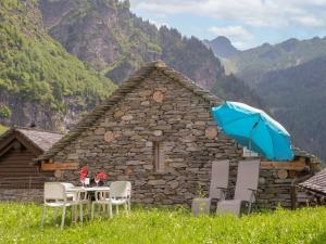a table with chairs and an umbrella in front of a building at Holiday Home Rustico La Dimora by Interhome in Malvaglia