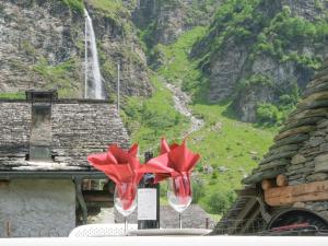 two red wine glasses on a table with a waterfall in the background at Holiday Home Rustico La Dimora by Interhome in Malvaglia