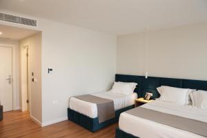 um quarto de hotel com duas camas e um corredor em Volmar Hotel em Durrës