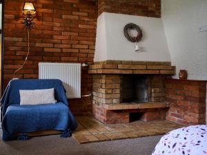 a living room with a brick fireplace and a blue chair at Apartment Harrachov 387 by Interhome in Harrachov